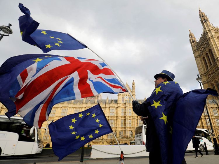 An anti-Brexit demonstrator waves a Union flag alongside a European Union flag outside the Houses of Parliament