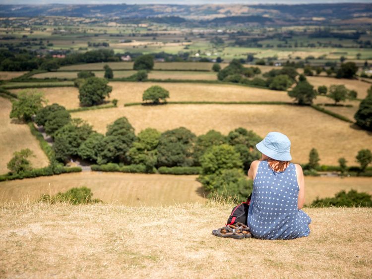 People sit on parched grass as they visit Glastonbury Tor in Glastonbury on July 24, 2018 in Somerset, England