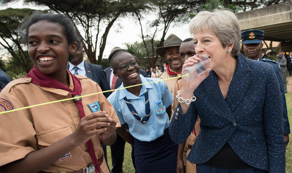 PM Theresa May testing out a plastic telephone with Kenyan scouts